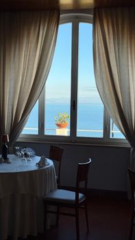 Elegant restaurant with a view of the ocean through a large window, enhancing dining ambiance.