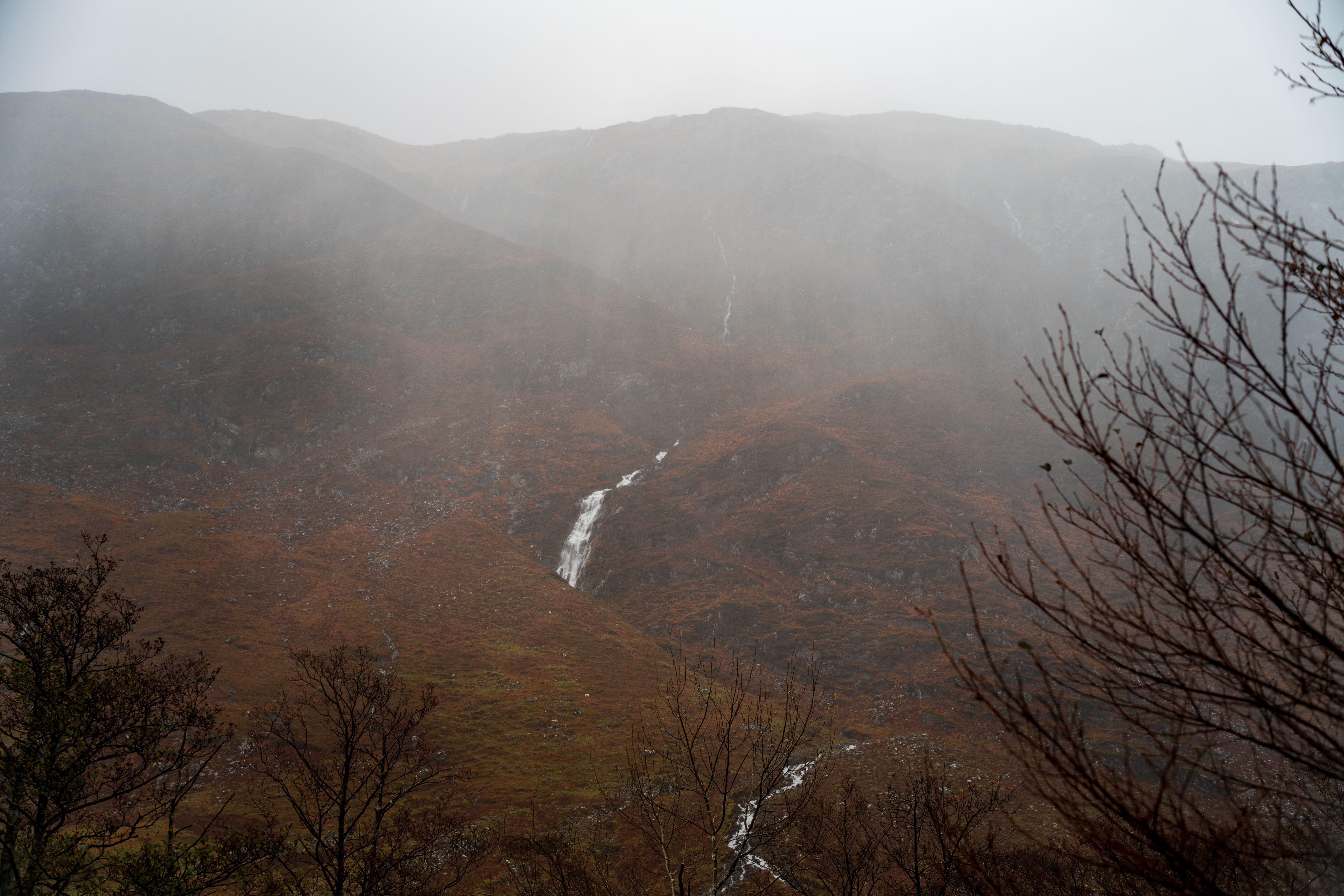 A scenic misty mountain view with cascading waterfall during autumn season.