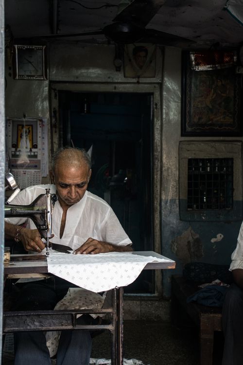 Free A dedicated tailor works on sewing fabric in a dimly lit indoor setting, capturing the essence of craftsmanship. Stock Photo