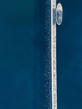 Drone shot of a pier and abandoned boat in Jönköping, Sweden, surrounded by calm blue waters.