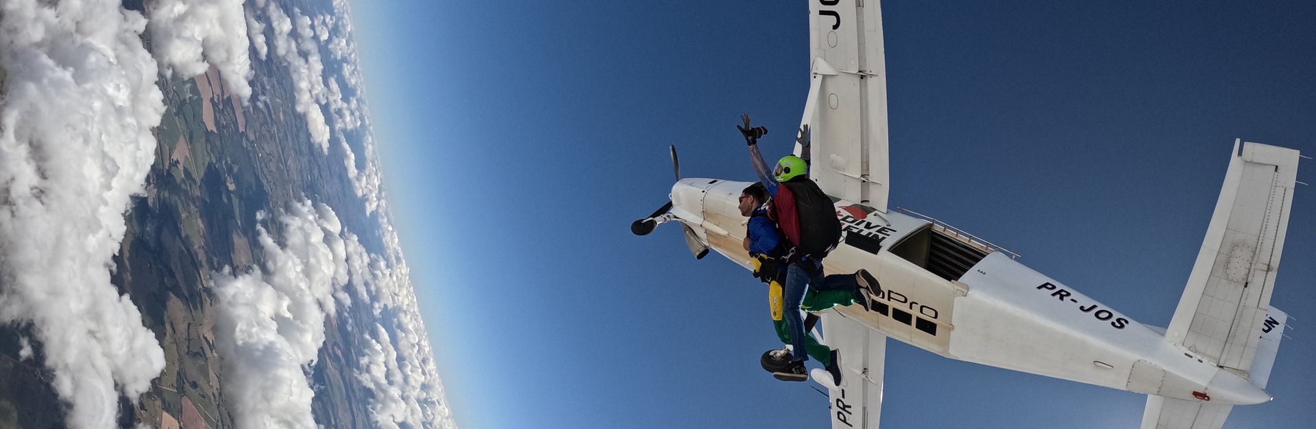 Exciting tandem skydiving jump from aircraft, high above scenic landscape.