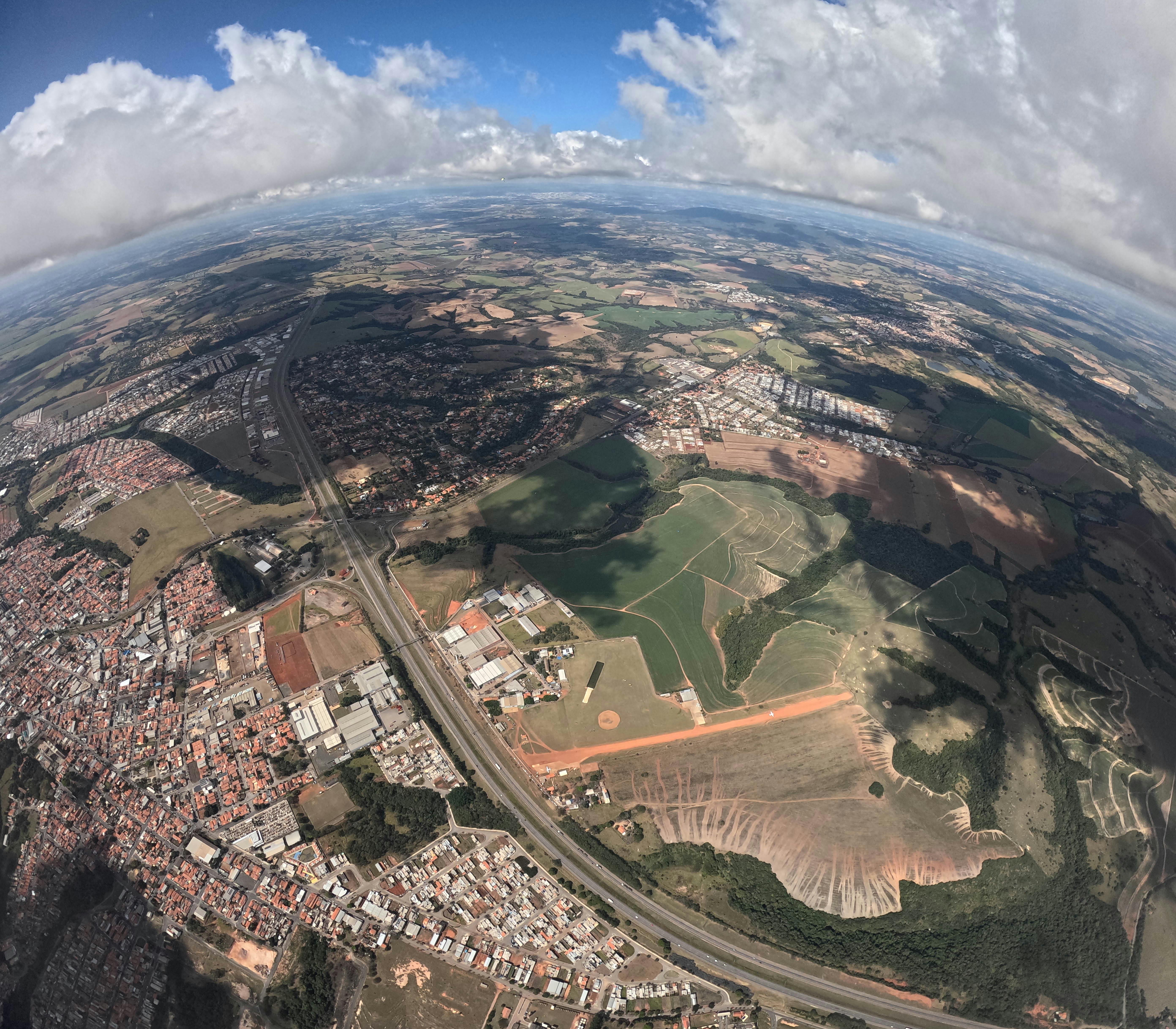Gorgeous aerial view showcasing urban and rural landscapes with fields and clouds.