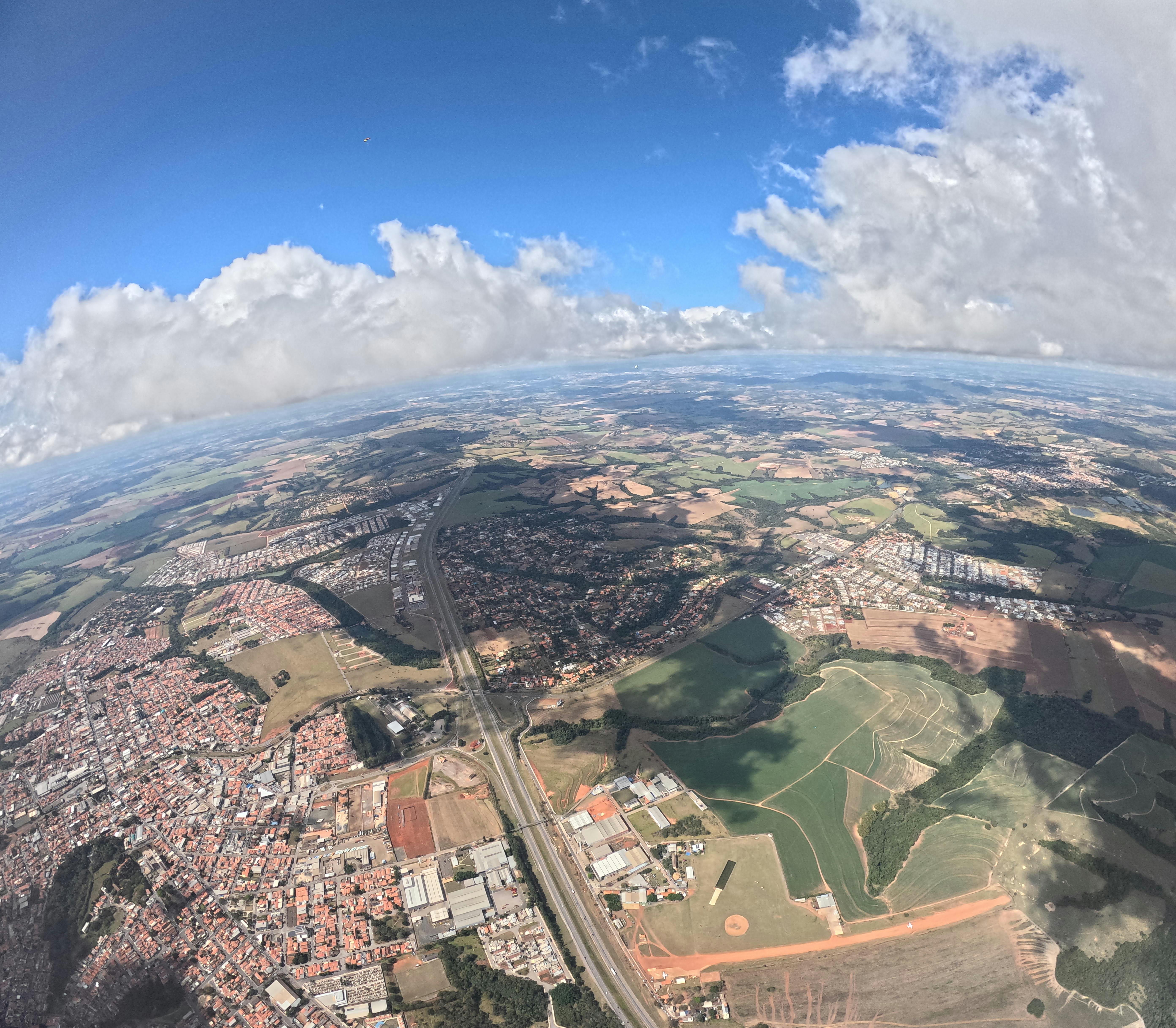 Expansive aerial view of a countryside cityscape under a vibrant blue sky with fluffy clouds.