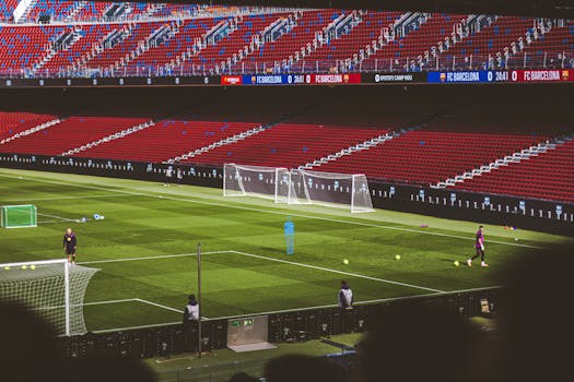 Soccer practice at a famous stadium with vibrant red seating and green field.