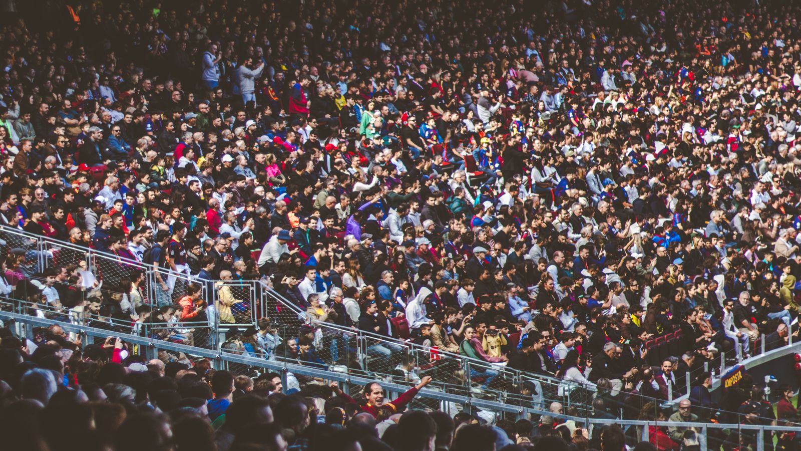 A vibrant football crowd filling a stadium during a daytime match