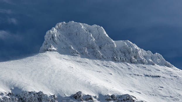 Stunning view of a snow-covered mountain peak against a clear blue sky, highlighting winter's beauty