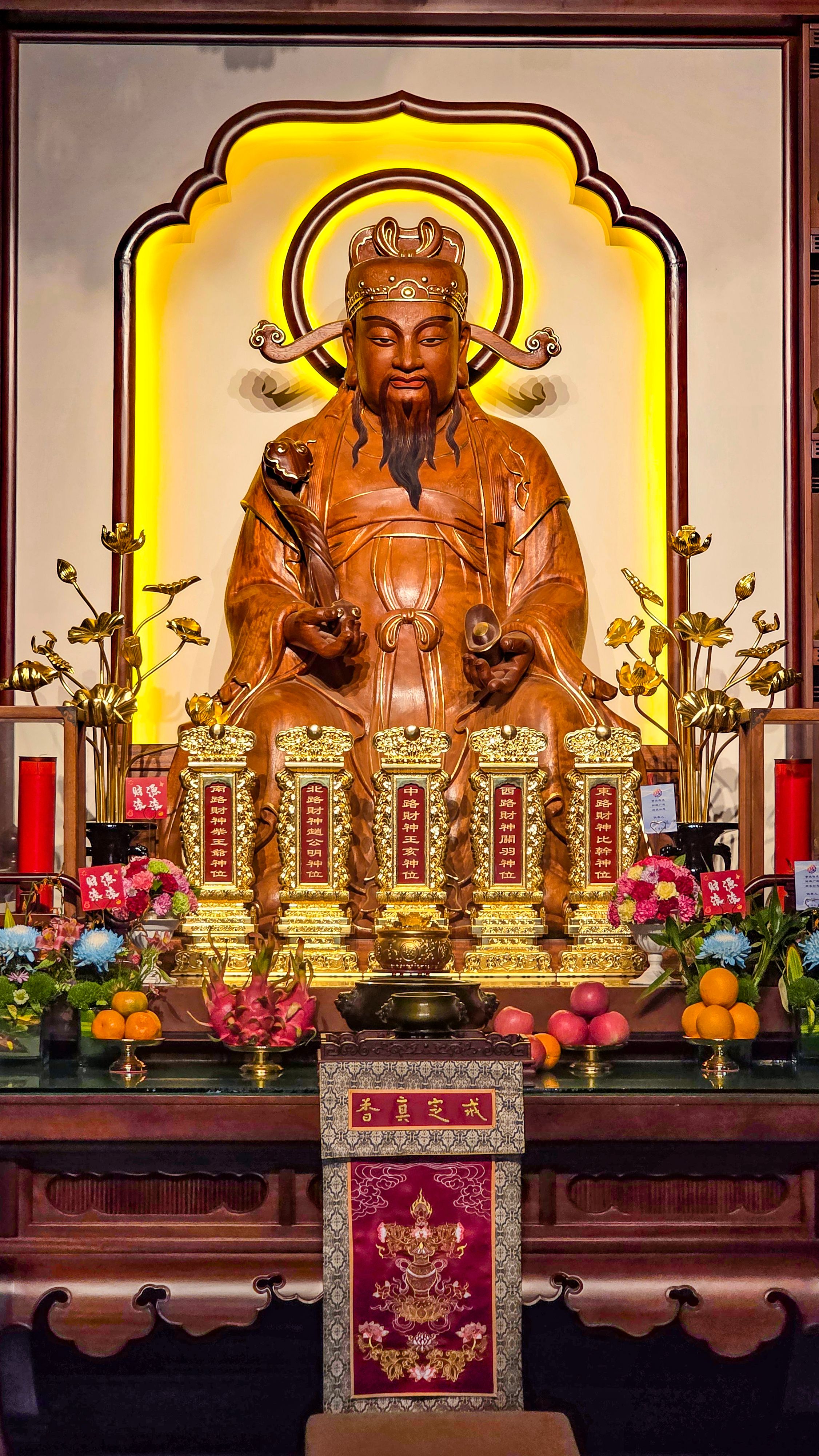 Intricate golden statue of a Chinese deity surrounded by offerings in Xi'an temple.