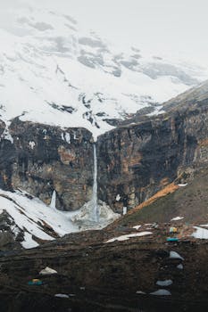 Breathtaking snow-capped mountain landscape with a cascading waterfall, ideal for nature and travel imagery