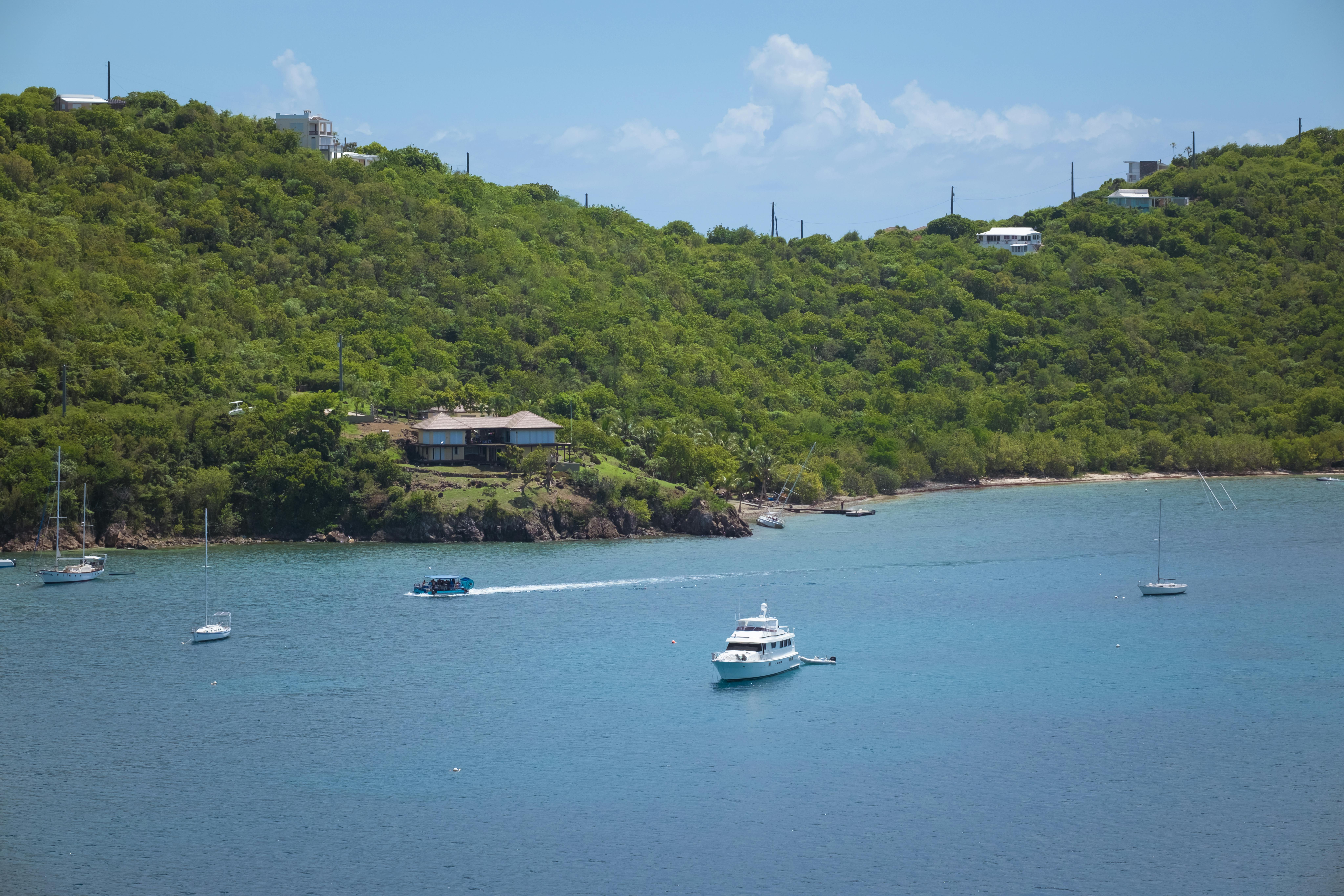 Beautiful coastal scenery with boats and lush green hills under a bright blue sky.