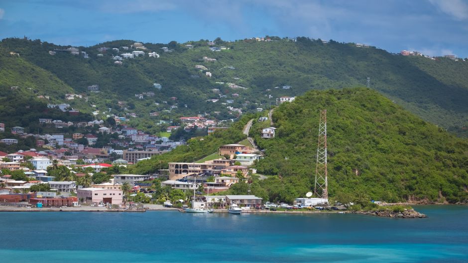 A picturesque coastal scene featuring lush green hills and vibrant turquoise waters.
