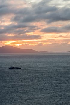 A boat sails across the sunset-lit waters near the Isle of Skye, Scotland.