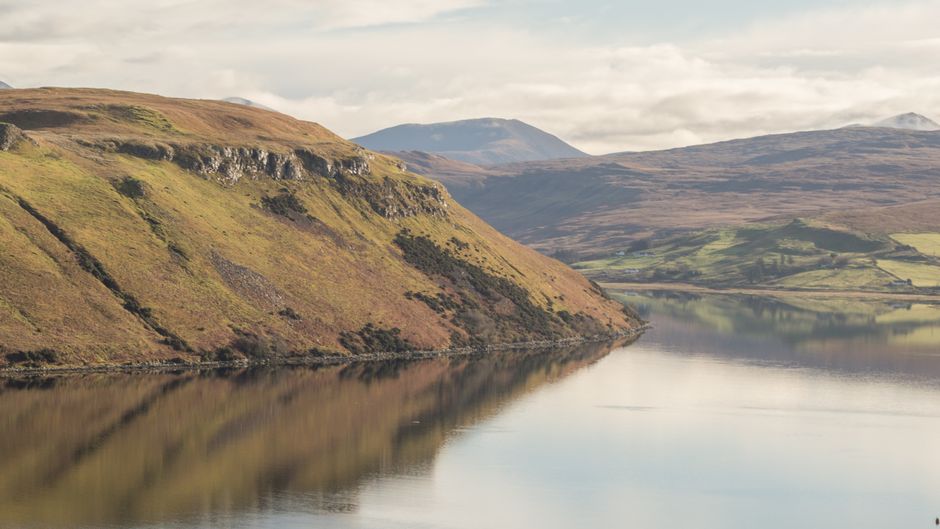 Beautiful landscape of Talisker Bay, Isle of Skye, Scotland with reflections and rolling hills.