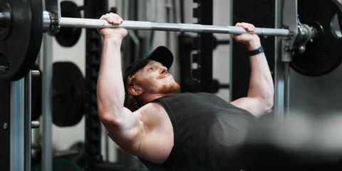 Adult male performing an incline bench press in a modern gym setting, showcasing strength and fitness.