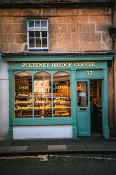 Quaint view of Pulteney Bridge Coffee shop with cakes display in Bath, UK.