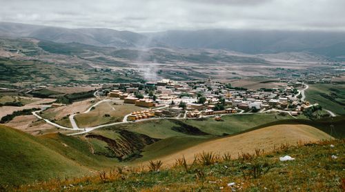 Free A tranquil mountain village surrounded by rolling hills under a cloudy sky, offering a picturesque landscape view. Stock Photo