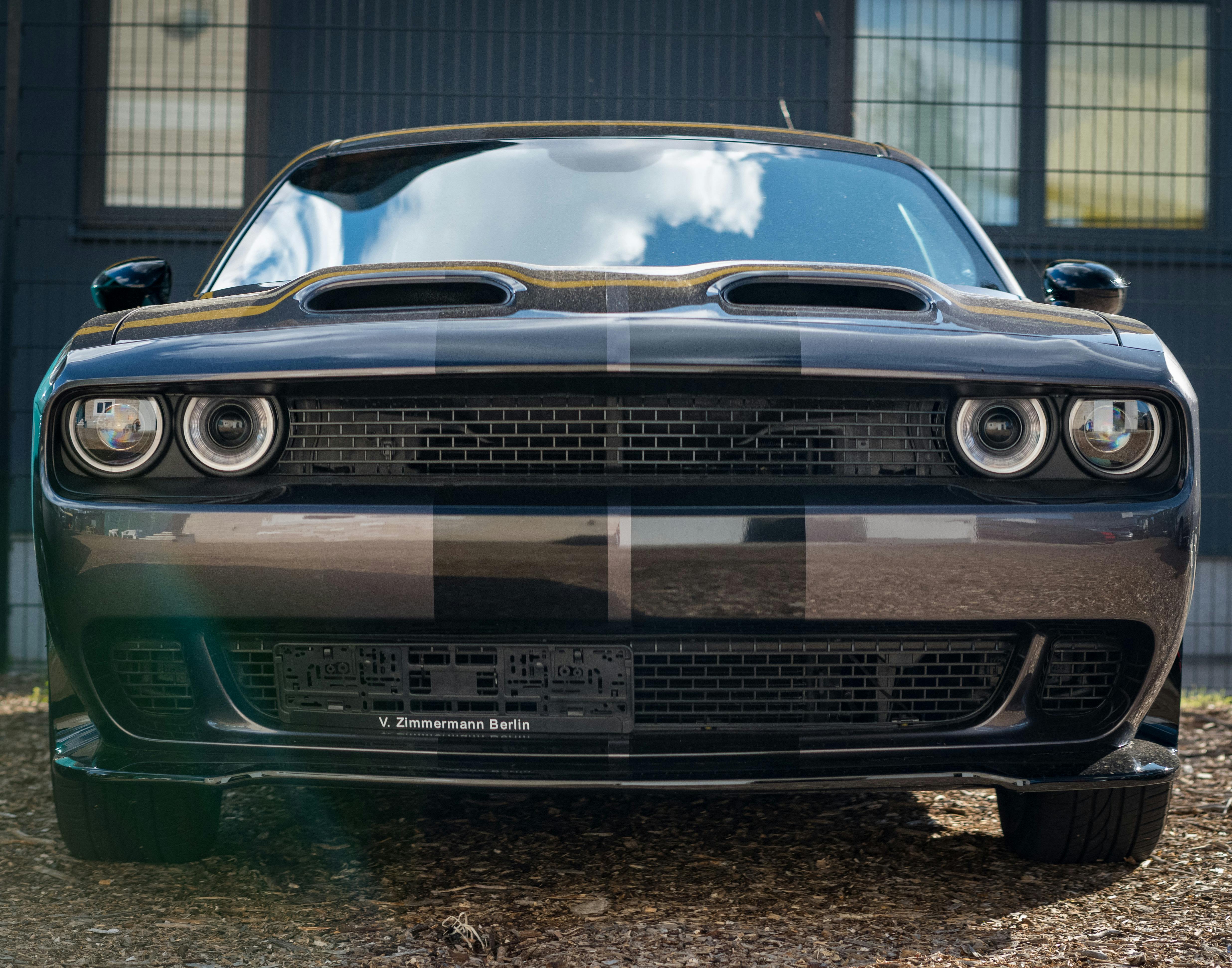 A sleek black Dodge Challenger car with distinctive grille design, photographed outdoors.