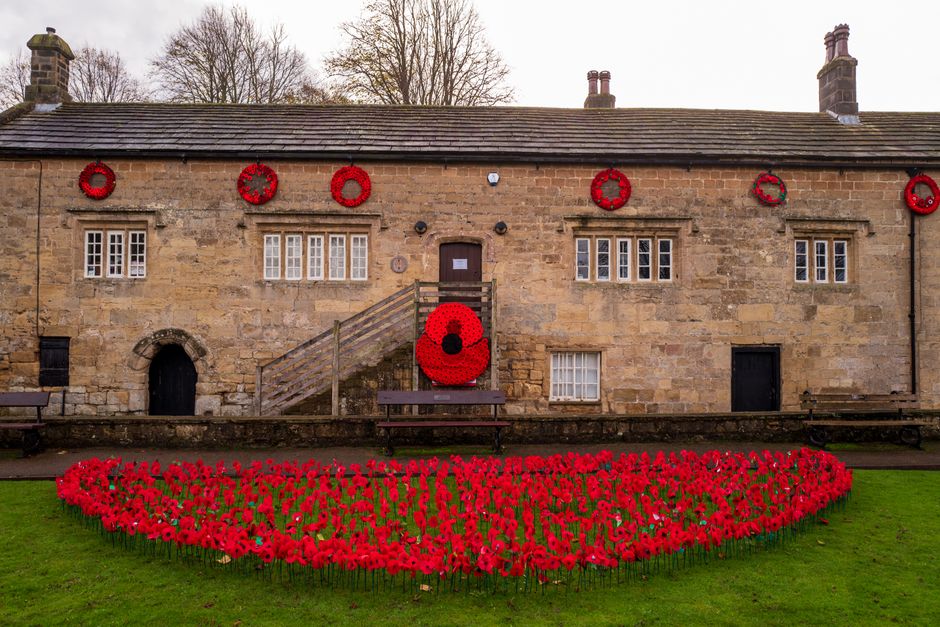 A historic English building adorned with poppies for Remembrance Day, symbolizing honor and memory.