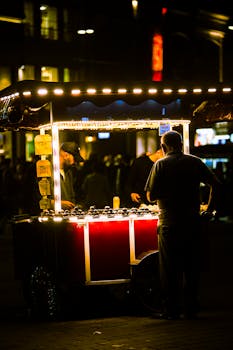Street vendor serving food at night under bright lights, urban atmosphere.
