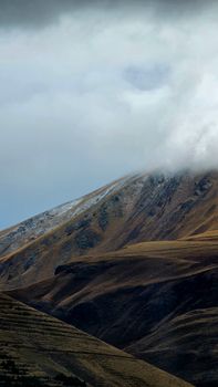 A dramatic and moody mountain landscape with a cloud-covered peak.