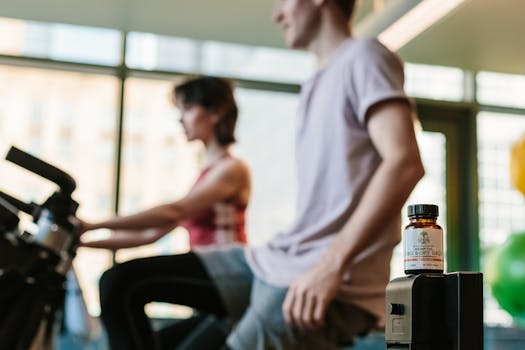 CBD gel bottle in gym with exercising adults, suggesting health benefits.