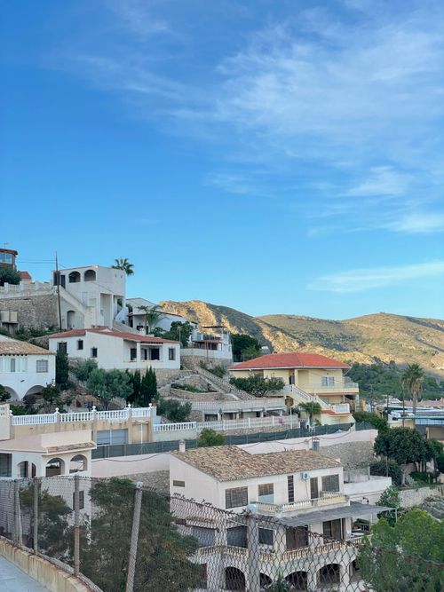 Free Charming Mediterranean hillside homes with mountain views under a clear blue sky. Stock Photo