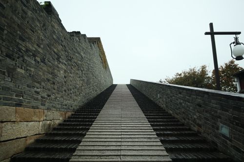 Free Linear perspective of a stone staircase ascending alongside a historic wall. Stock Photo