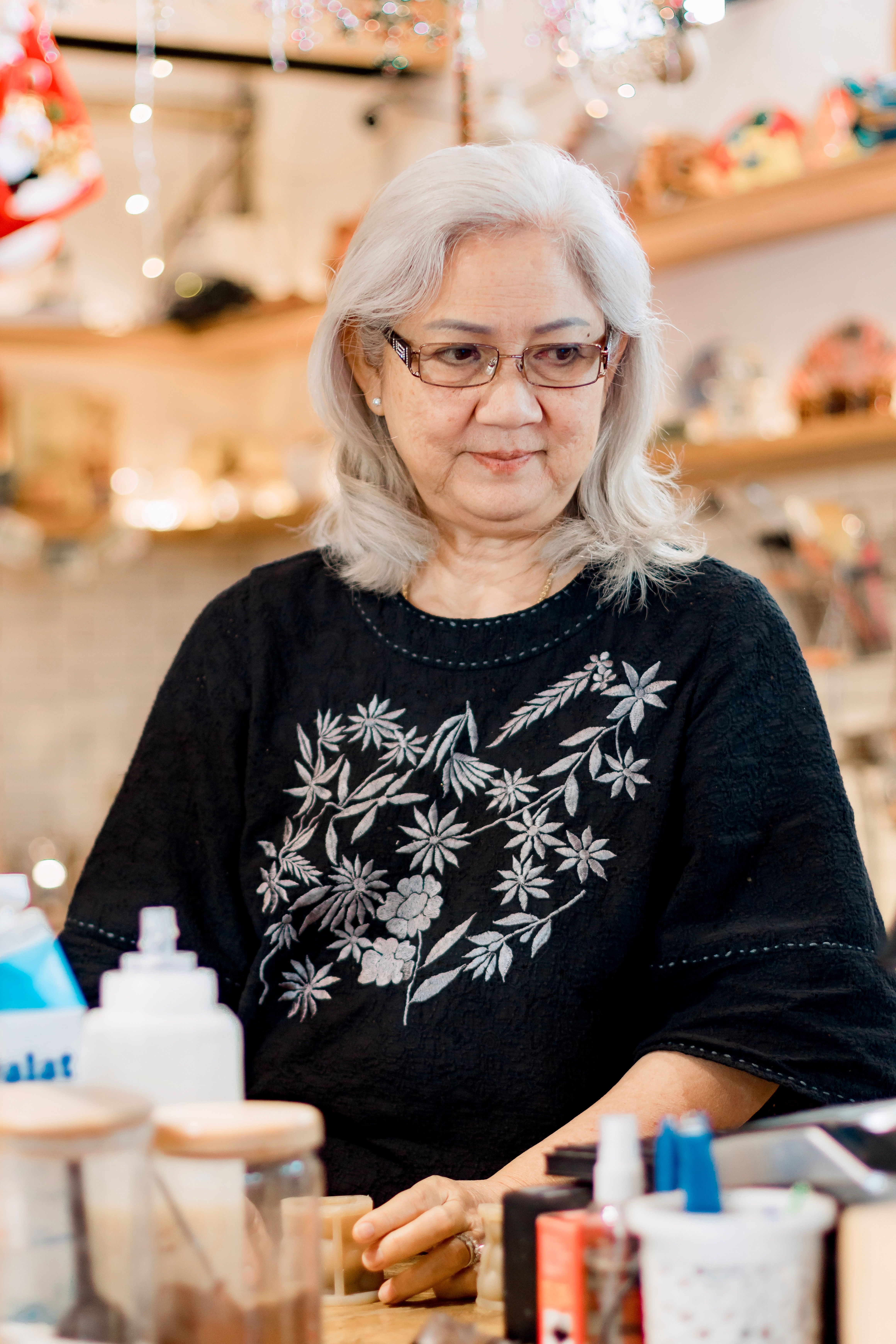 Elderly woman with gray hair in a cozy, artistic café environment.