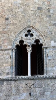 Detailed view of a gothic-style window on an old stone building, showcasing historic architecture.