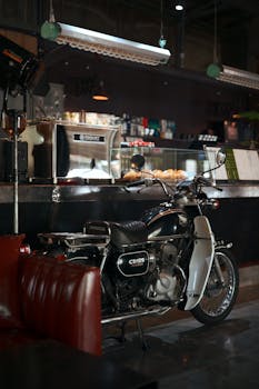 Classic Honda CD125 motorcycle parked inside a cozy cafe with vintage decor.