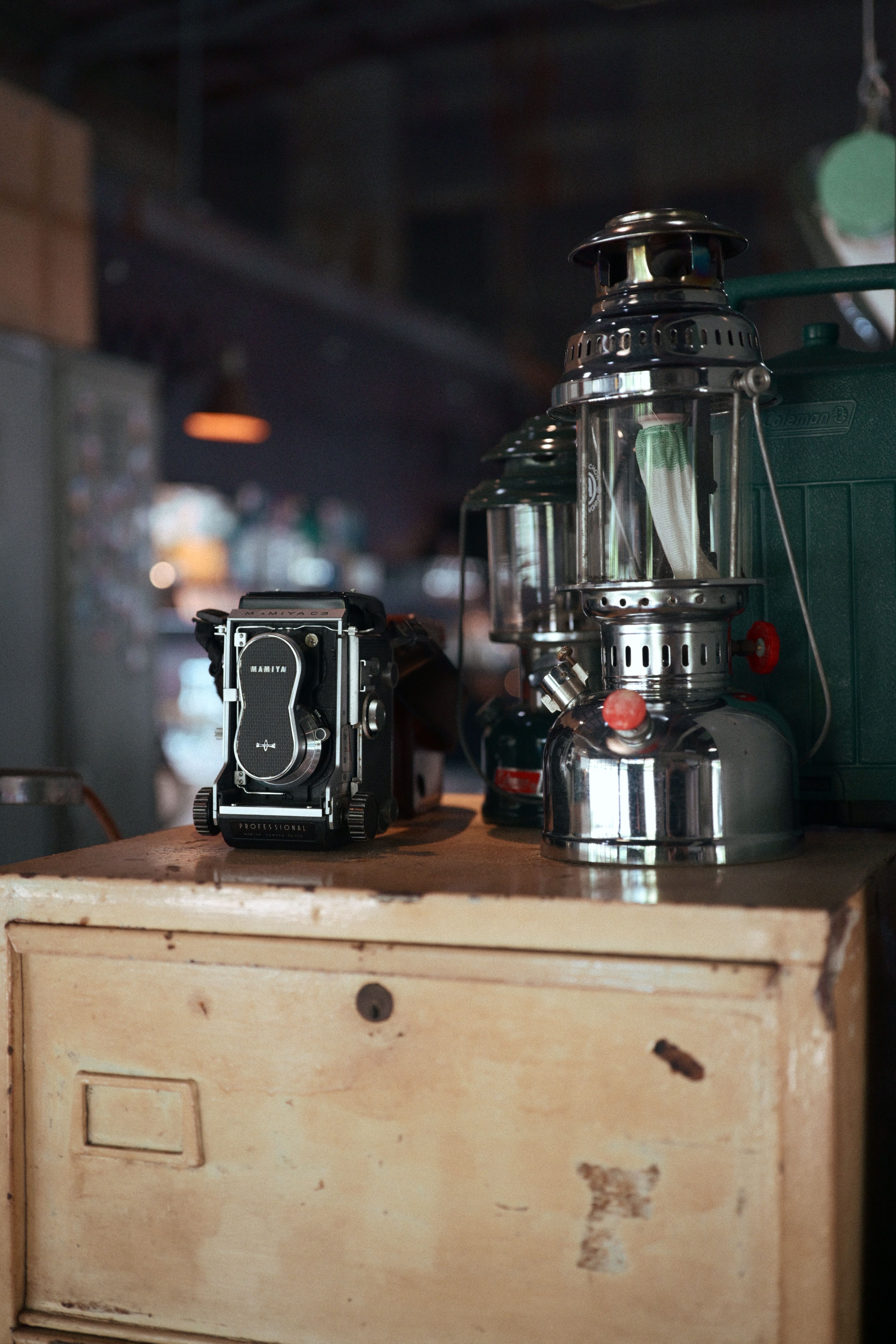 A vintage camera and retro lanterns on a rustic wooden cabinet in a vintage setting.