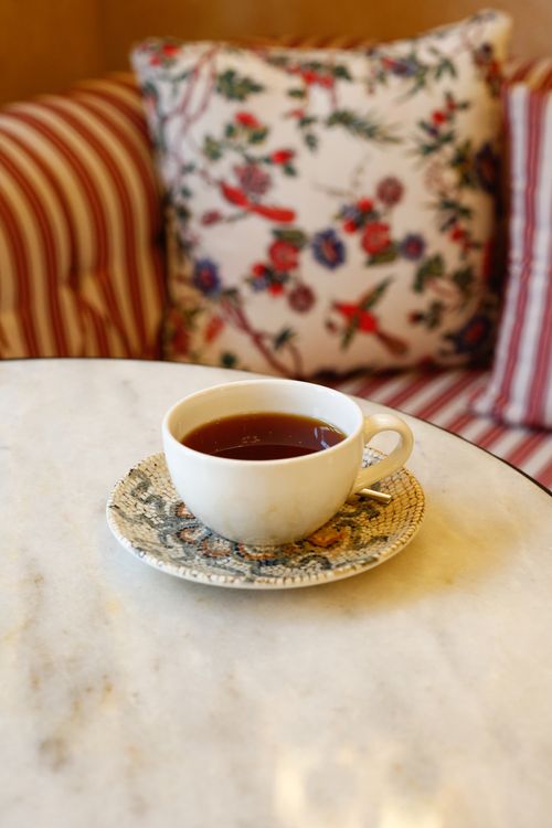Free A floral tea cup on a marble table with cozy cushions in a home setting. Stock Photo