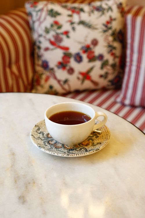 Free A warm cup of tea on a marble table with a floral and striped backdrop. Stock Photo