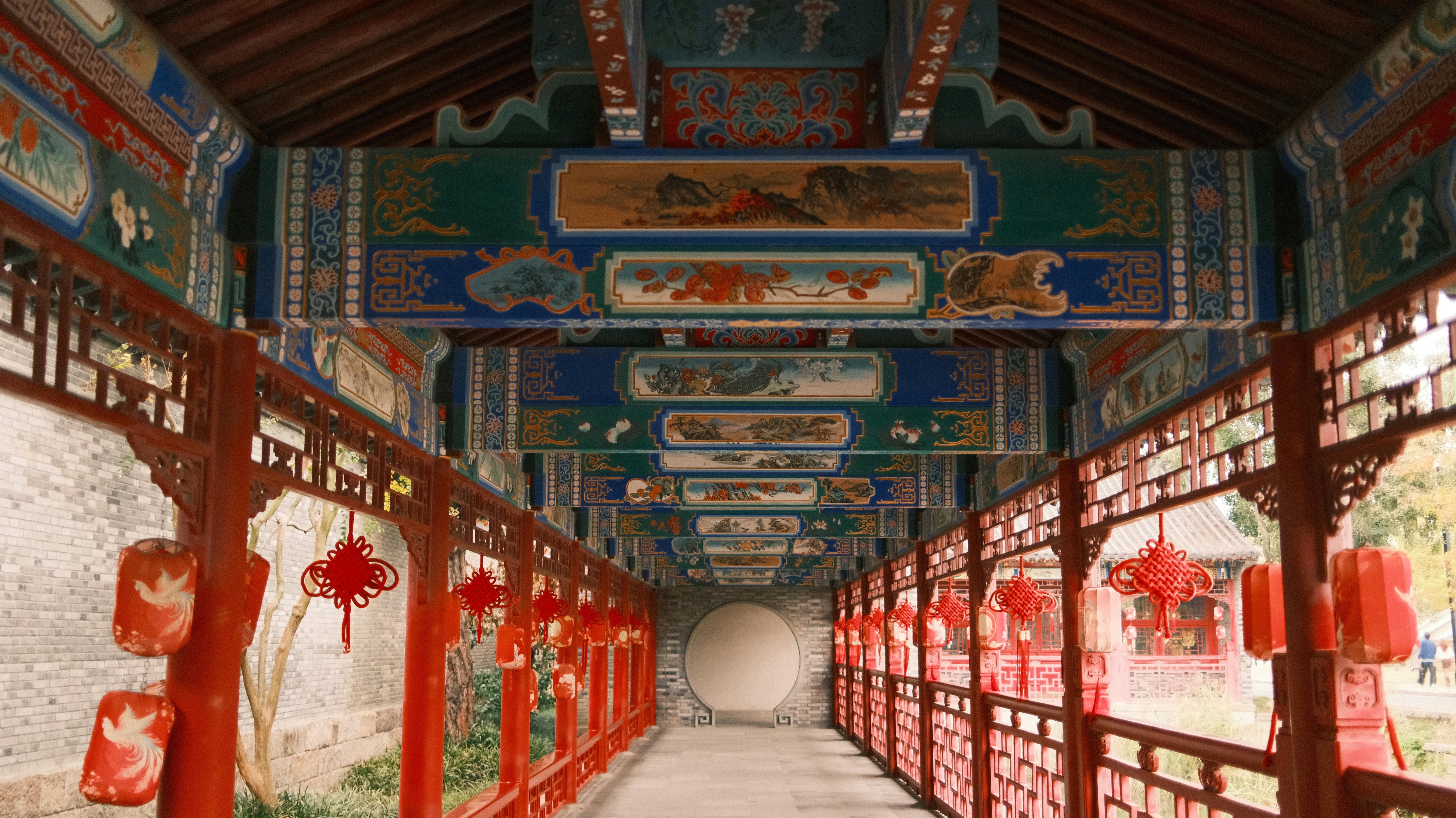Beautifully decorated corridor in traditional Chinese architecture, adorned with red lanterns and intricate artwork.