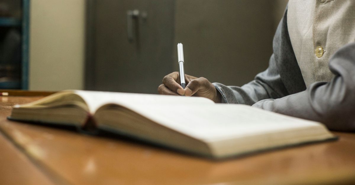 Student Writing Notes in a Library Setting · Free Stock Photo