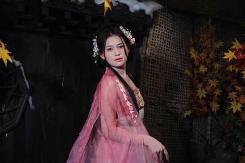 Free A woman in a pink traditional dress stands elegantly indoors with autumn leaves, reflecting a serene vibe. Stock Photo