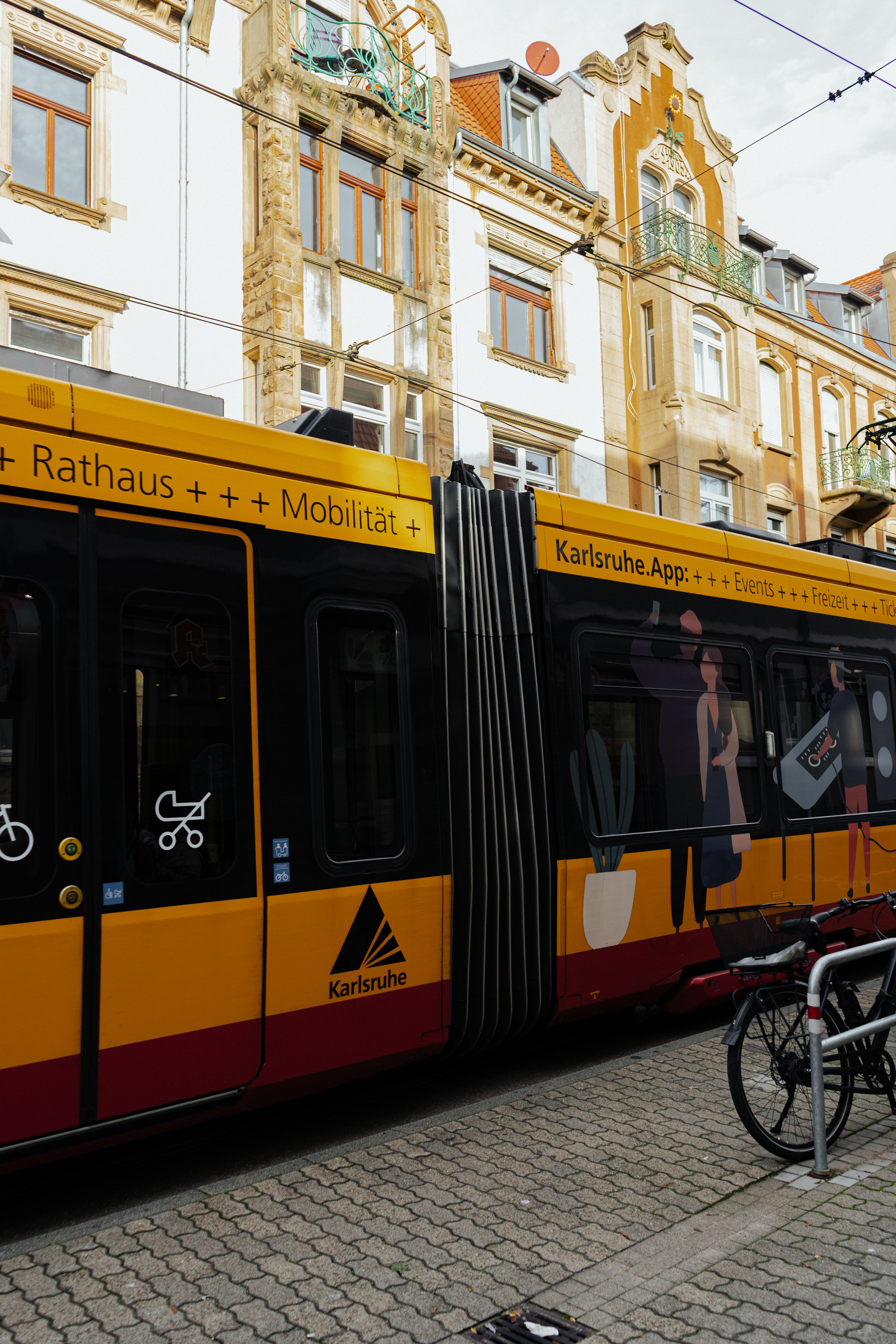 A vibrant yellow tram runs through the historic streets of Karlsruhe, Germany.
