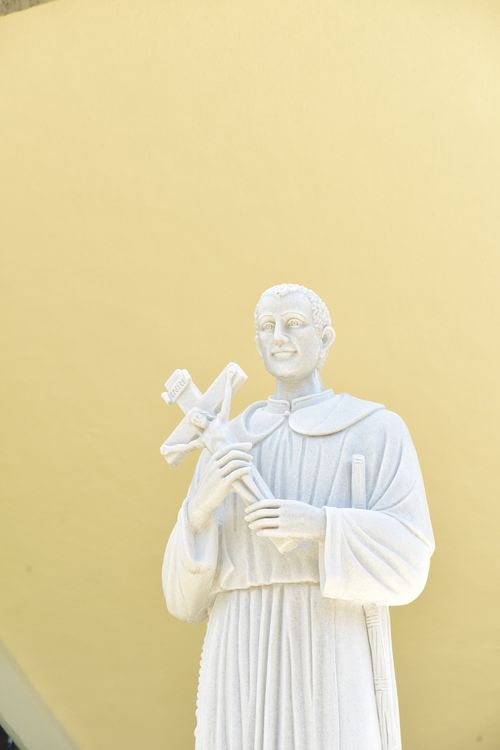 Free A close-up view of a white stone statue of a saint holding a crucifix with a serene expression. Stock Photo