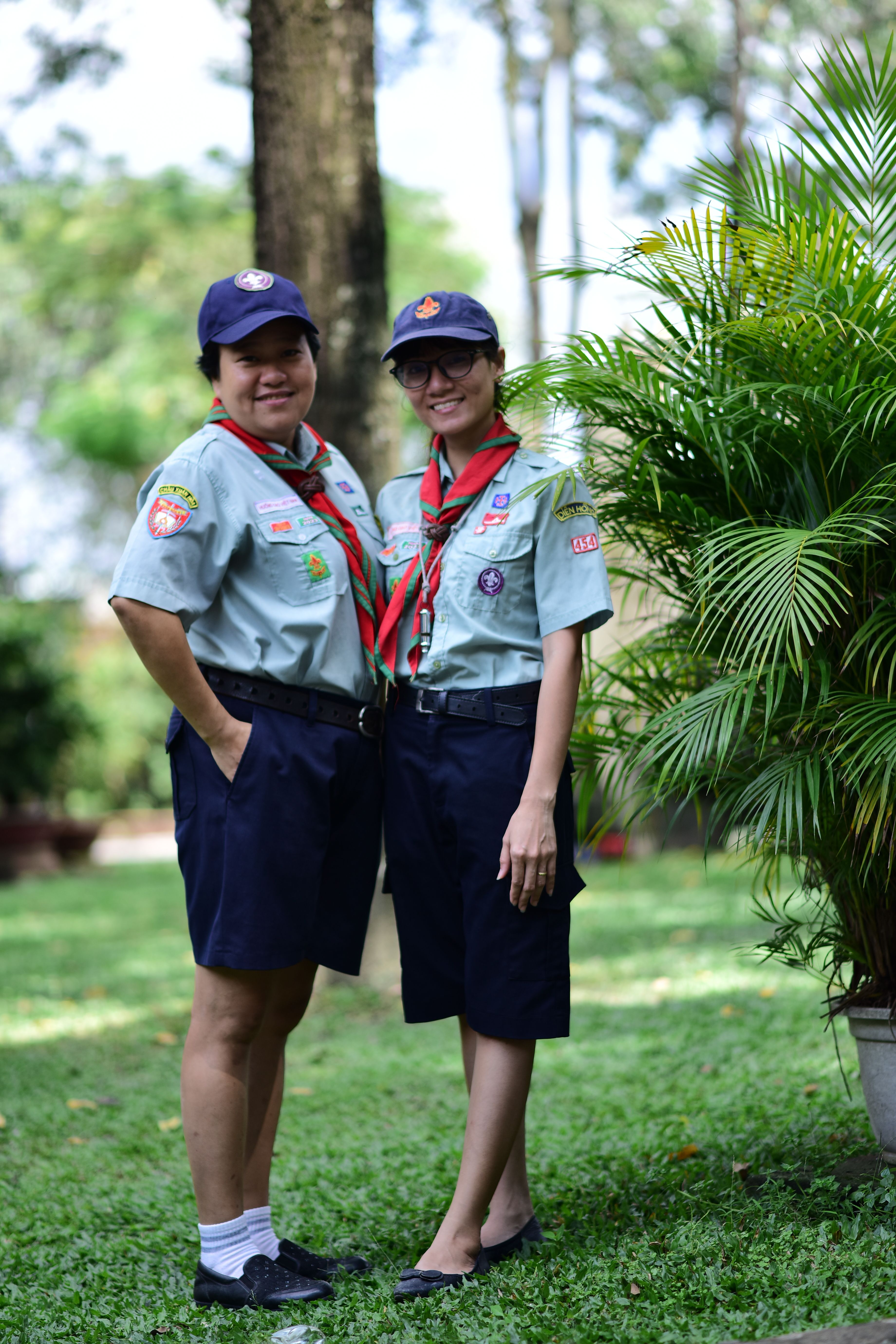 Two scout leaders proudly pose outdoors in their uniforms, conveying teamwork and leadership.