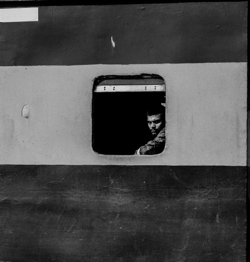 Free Moody black and white photo of a man looking out from a train window, capturing solitude and travel. Stock Photo