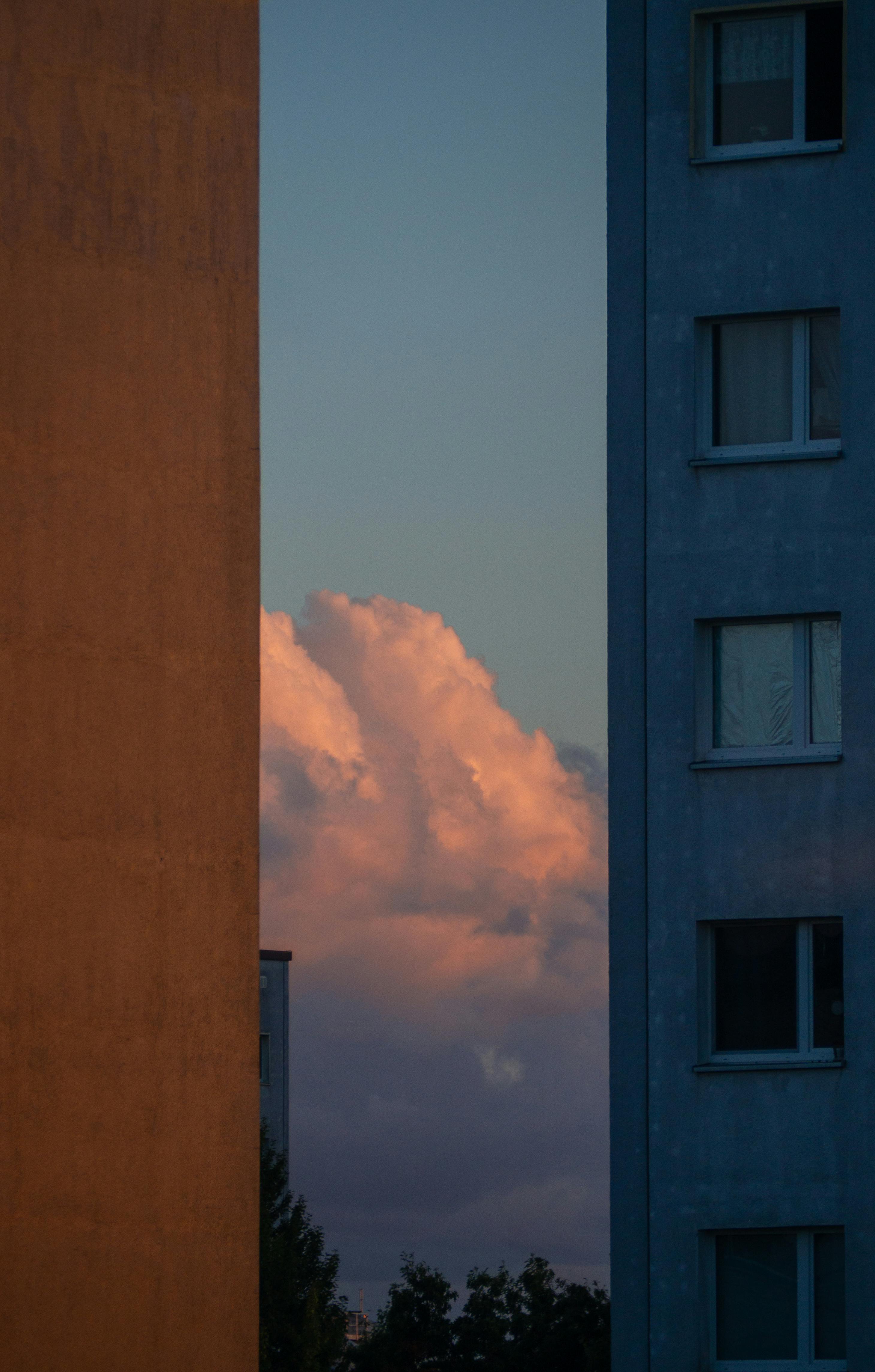 A beautiful sunset sky with dramatic clouds framed by two urban high-rise buildings.