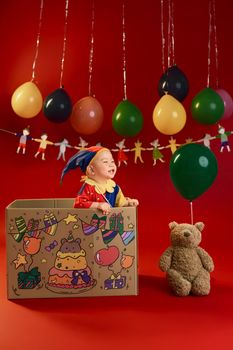 Cute baby in a festive setting with balloons, teddy bear, and colorful decorations, ideal for children's celebrations.