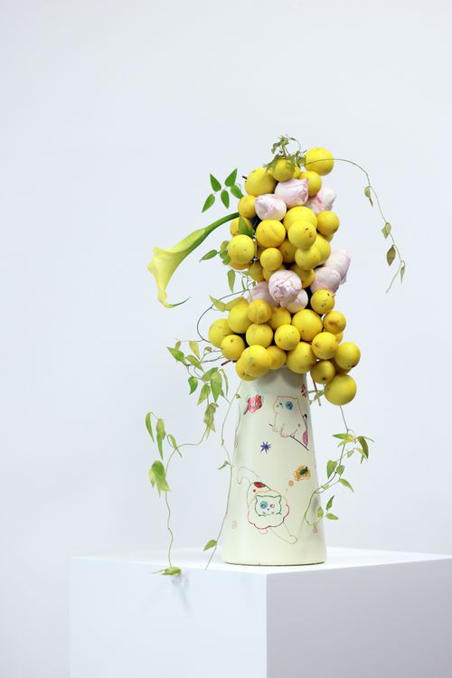 Free Unique floral arrangement of lemons and greenery in a decorative vase. Minimalistic and artistic composition. Stock Photo
