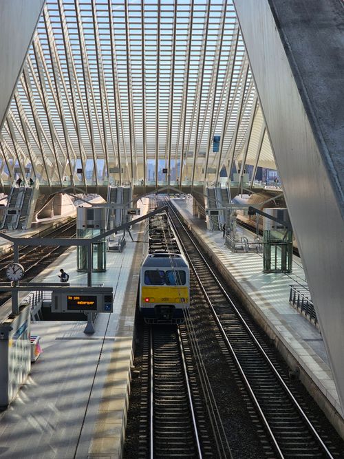 Free Modern train station in Liège with striking architectural design and a train on the tracks. Stock Photo