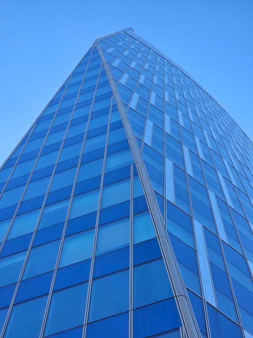 Free Tall modern skyscraper with blue glass panels against a clear sky in Belgium. Stock Photo