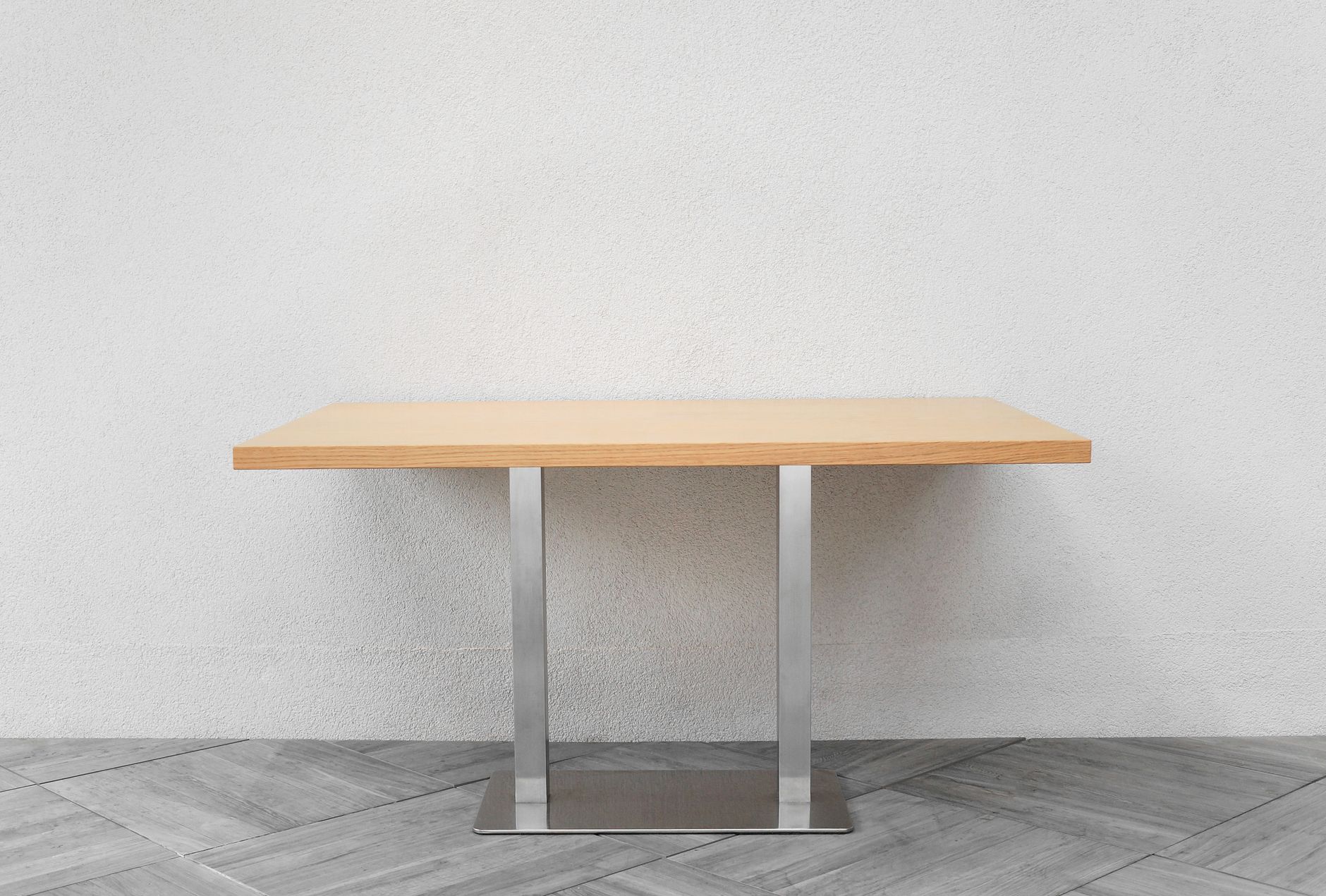A simple and elegant minimalist wooden table set against a plain white wall.