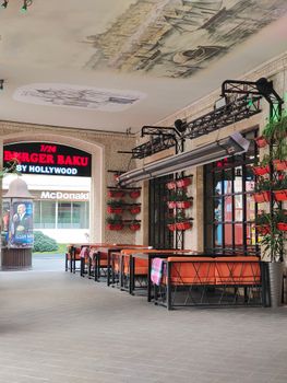 Stylish outdoor seating area with tables and decor under artistic ceiling, near popular fast food locations.