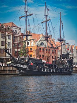A stunning historical pirate ship docked against colorful buildings in Gdańsk, Poland.