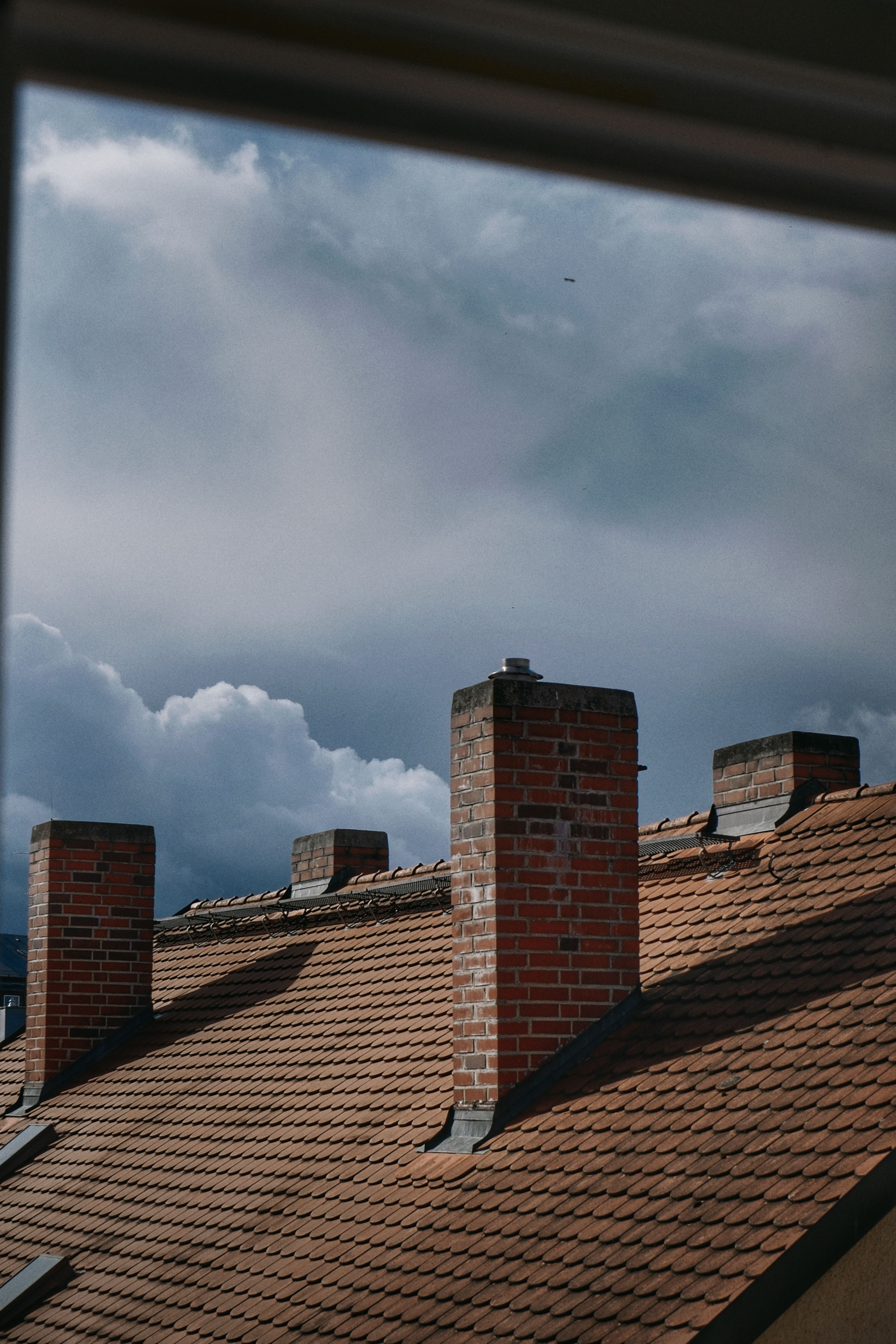 Brick Chimneys on Rooftop Against Cloudy Sky · Free Stock Photo