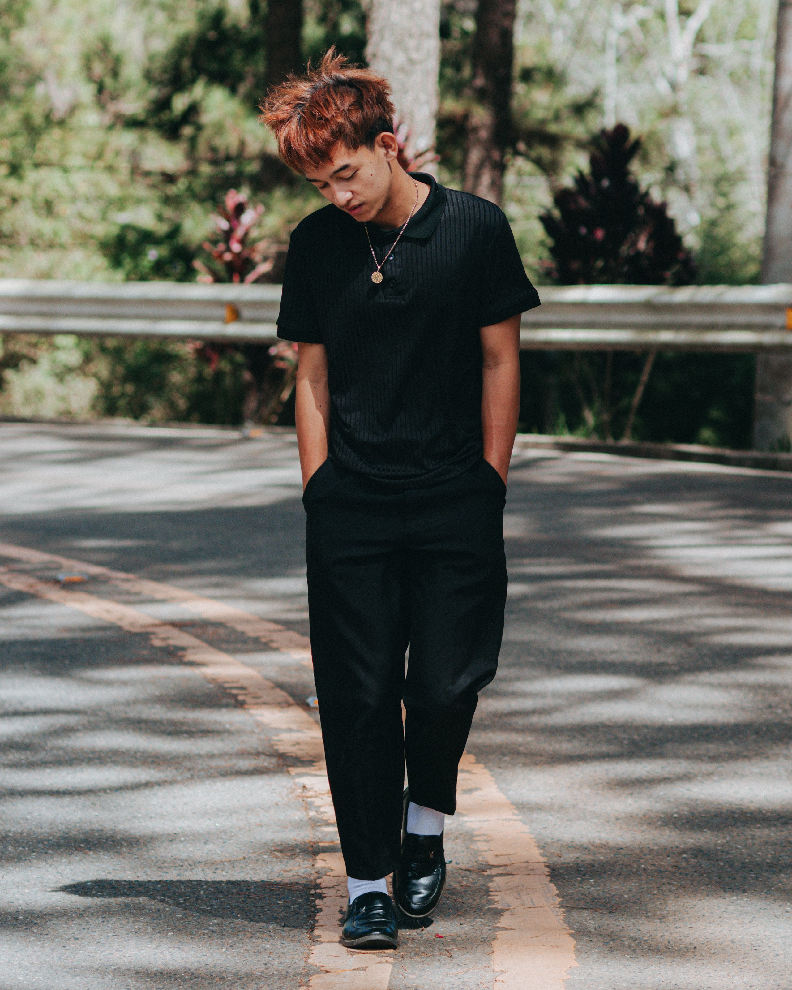 Young Man Walking on Sunlit Forest Road · Free Stock Photo