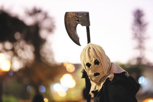 A mysterious figure with a sack mask and axe at Halloween celebration in Arequipa, Peru.